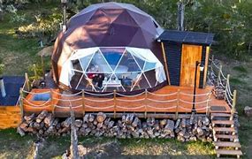 Glamping Isla Leones – Patagonia Coast, Argentina 2 Glamping dome on as platform with logs stacked on the ground with a porch platform with steps.