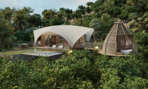 Eco hotel with two buildings, outdoor chairs, and a pool, surrounded by lush rainforest.