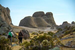 Eco-Camp Near Marcahuasi Stone Forest 3 Two people trail hiking with backpacks near large rock formations and vegetation