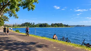 Lakeside Cabins At Represa De Guarapiranga: A Waterside Glamping Escape 3 Cyclists and walkers enjoying a scenic waterfront path beside Represa de Guarapiranga in São Paulo, Brazil.