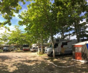 Campers with trees and tent and a parking lot.