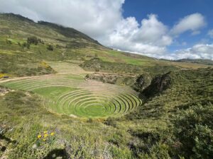 🏨 Tambo Del Inka (Urubamba) – Luxury & Adventure In the Sacred Valley 3 Ancient ruins in a valley with vegetation and hill on a partly cloudy day.