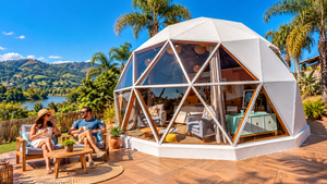 Guararema Riverside Glamping, Brazil: A Peaceful Escape by the Water 2 Luxury white geodesic glamping dome with panoramic windows, wooden deck, and a couple relaxing with drinks, surrounded by tropical palm trees, green hills, and riverside scenery inspired by Guararema, Brazil.