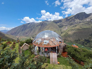 Luxury Dome Camp, Ollantaytambo: Glamping In The Heart Of The Sacred Valley 1 Luxury glass geodesic glamping dome perched on a mountainside overlooking a lush valley, surrounded by dramatic Andes mountains and blue skies near Ollantaytambo, Peru.
