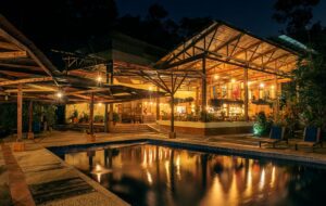 Casa De Adobe Eco-Lodge: Sustainable Luxury in the Heart of South America 3 Lodge with a swimming pool with chairs and well lit up building with trees at night.