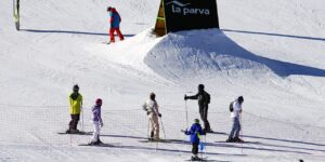 Several people learning how to ski with a sign and lots of snow on the ground.