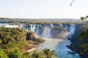 Panoramic view of Iguazú Falls with cascading waterfalls surrounded by lush tropical rainforest.