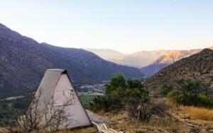 Glamping structure on a platform with trees and vegetation with mountains.