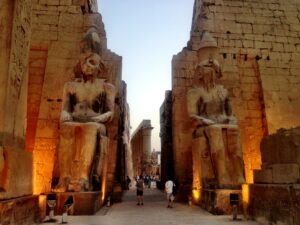Karnack Temple statues and an ancient ruin location in Egypt with a walkway and people.