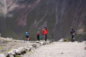 La Parva Mountain Retreat: A High-Altitude Escape in the Andes 7 Group of four mountain bikers wearing helmets and outdoor clothing on a rocky mountain trail, with bicycles and steep mountain slopes in the background.