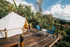 Luxury glamping tent on a private wooden deck surrounded by lush mountain and canyon scenery.