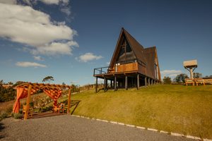 A-frame luxury lodge with outdoor seating and mountain surroundings in Cajón del Maipo, Chile.