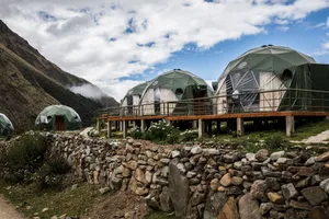Geodesic glamping domes on raised platforms surrounded by rugged Andean mountain scenery near Ausangate, Peru.