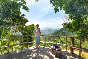 Traveler enjoying panoramic rainforest and mountain views from a wooden lookout in Rio de Janeiro.