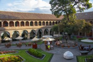 Hotel with a table and chairs with umbrellas and a tree with vegetation and flowers.