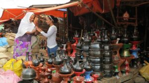 Two women at a market with goods being displayed and pottery at Addis Ababa