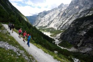 🏔️ Reintal Route: The Easiest Trail To Zugspitze, Germany 3 Hikers walking along a scenic mountain trail, carrying backpacks and trekking gear, surrounded by lush forests and alpine landscapes.