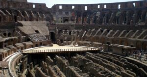 Interior of the Colosseum in Rome with visitors exploring the arena and seating areas.
