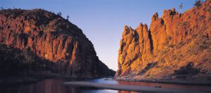 View of a canyon with steep rocky walls, a river flowing through the bottom, and trees along the riverbanks.
