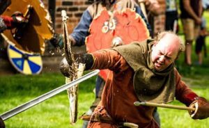 Guided Tours and Reenactments: Experiencing the Viking Age 4 Vikings of Middle England reenactors in full costume demonstrating battles, crafts, and daily life at a public event.