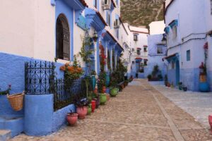 Blue-painted buildings lining a narrow street in a Moroccan town.