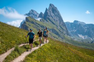 Dolomites Alta Via Trails: Ultimate Hiking Adventures in Italy 2 Four hikers with backpacks walking on a mountain trail surrounded by dramatic peaks and alpine scenery.