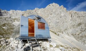 A tiny alpine hut in Slovenia, nestled in rugged mountains, offering a cozy refuge for hikers in a dramatic alpine landscape