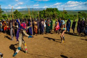 Villagers in Ethiopia’s Omo Valley participating in a traditional competition, carrying sticks across an open field.