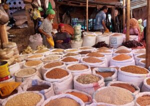 People at Colorful spices displayed at a bustling market in Addis Ababa, Ethiopia, with shoppers browsing local goods.
