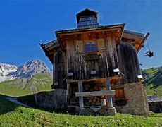 A small alpine house on a hilltop in the Italian Dolomites, surrounded by mountains and dramatic landscapes.