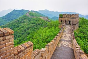 🛤️ History of the Great Wall 3 View from the walkway of the Great Wall of China, with the stone path stretching forward and lush green vegetation on both sides.