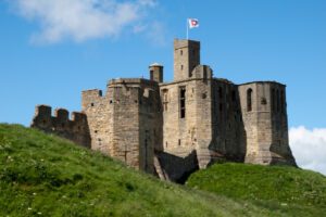 Historic castle in England surrounded by lush green landscape, showcasing medieval architecture.