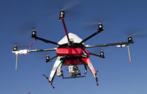 🌞🚁🤖Top 25 Drones Under $1,500 For Travel & Adventure 1 Red, white, and black drone with propellers and camera, ready for aerial photography and outdoor adventures.