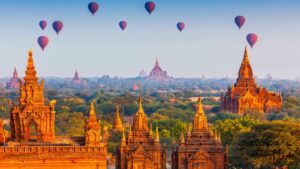 🌄 Explore Bagan, Myanmar: Ancient Temples, Hot Air Balloons & Timeless Adventures 2 “Nine hot air balloons floating over Bagan, Myanmar, with ancient temples, pagodas, and lush greenery below.