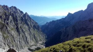 Panoramic view from the summit of Zugspitze via the Höllental Route, showing alpine peaks, valleys, and distant mountains under a clear sky.