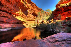 View of a canyon with steep rocky walls surrounding a large pond, reflecting the natural landscape above.