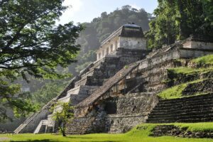 Explore the ancient Mayan ruins of Palenque in Mexico, surrounded by lush jungle and featuring pyramids, temples, and historic structures.
