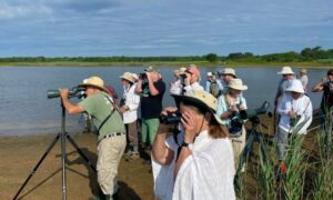 Group of people birdwatching beside a lake in South America.