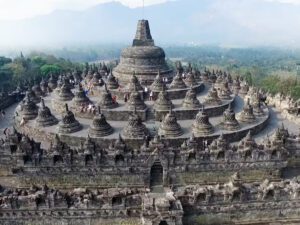 🌄 Explore Borobudur, Indonesia: Majestic Temples, Sunrise Views & Cultural Adventures 2 Aerial view of Borobudur Temple in Indonesia, showing acorn-shaped stupas, surrounding temples, and the lush mountain landscape.