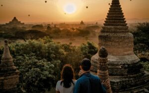 🌄 Explore Bagan, Myanmar: Ancient Temples, Hot Air Balloons & Timeless Adventures 5 Two people standing in front of an ancient temple in a misty forest in Bagan, Myanmar, with other temples visible in the distance.