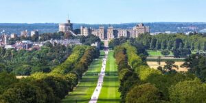 History Of Windsor CastleWindsor Castle Was Originally Built In 1070 2 Distant view of Windsor Castle and Buckingham Palace, iconic landmarks in England, with surrounding landscape.