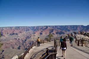 Many people standing at the top of the Grand Canyon, looking out at the breathtaking scenery