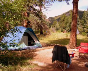 Camping tent with two chairs set up in a forested campground
