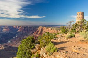 🏛️ Desert View Watchtower – Grand Canyon South Rim 3 View from the top of a canyon showing a historic tower and the Colorado River flowing through the canyon with steep cliffs on either side.