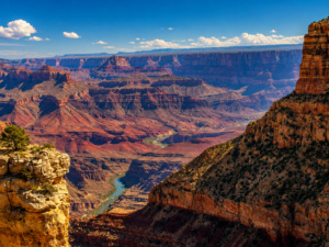 🌅 Desert View Drive – Grand Canyon Scenic Route 5 Panoramic Grand Canyon landscape featuring towering canyon cliffs, layered red rock formations, and the winding Colorado River flowing through the vast desert canyon beneath clear blue skies.