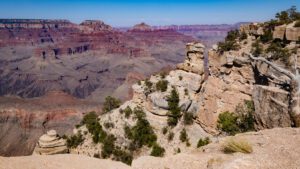 Looking down into the Grand Canyon from a high ledge with steep canyon walls and layered rock formations.