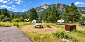 Aspenglen Campground with RVs, tents, picnic tables, pine forests, and mountain scenery in Rocky Mountain National Park, Colorado.