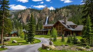 Tower Fall – Yellowstone’s Classic Waterfall 2 Rustic Yellowstone-style lodge and cabins surrounded by evergreen forest, mountain scenery, and a waterfall on a bright summer day.