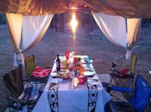 🎄✨ Holiday Glamping Must-Haves: 50 Products For Festive Outdoor Getaways 4 Glamping structure with flaps pulled aside, revealing a wide-open view, a table set with camping chairs, and ready for a meal.