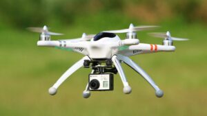 White drone with red markings and glowing green lights captures stunning aerial views over scenic landscapes.